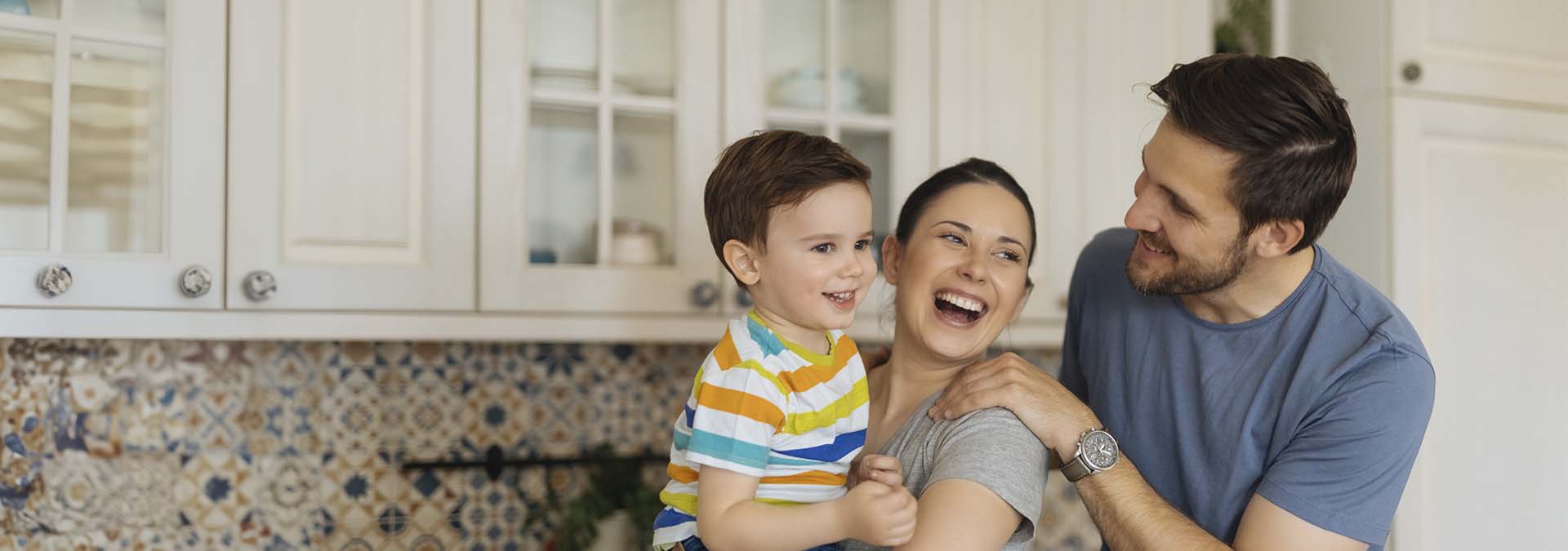 young couple and child smiling in kitchen