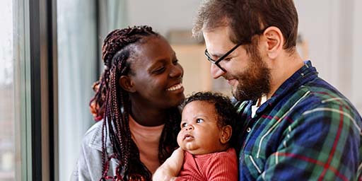 couple smiling and holding toddler 