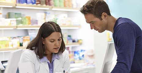 man talking to pharmacist at counter