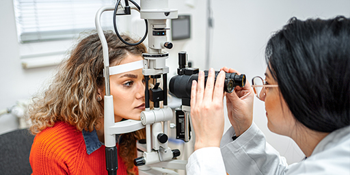 Ophthalmologist performing eye exam with optical equipment on female patient