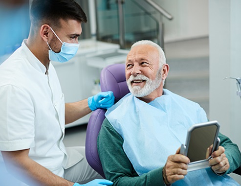 Happy senior man talking to his dentist while being satisfied with dental procedure at dentist's office.