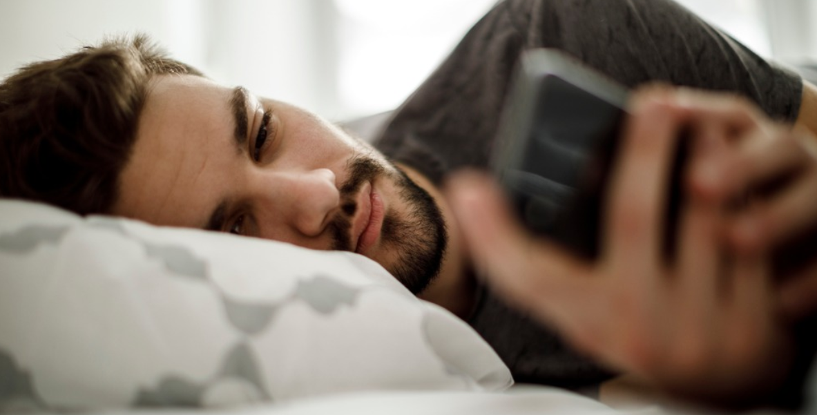 man with phone on bed