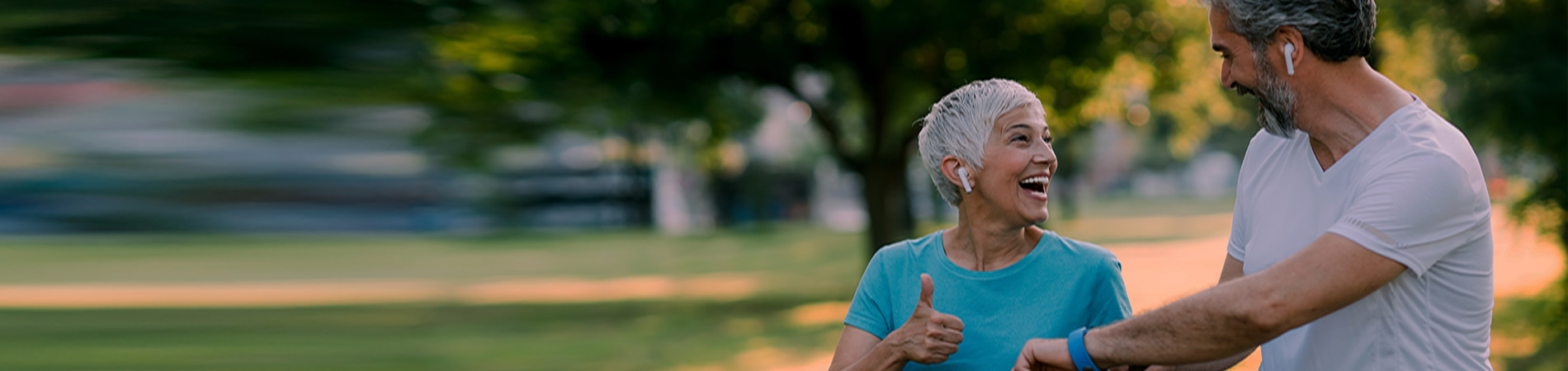 Smiling mature couple in sports wear jogging together and checking the time at smartwatch.