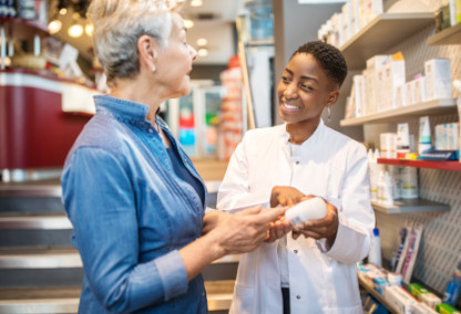 Young pharmacist smiling and helping older woman with medication