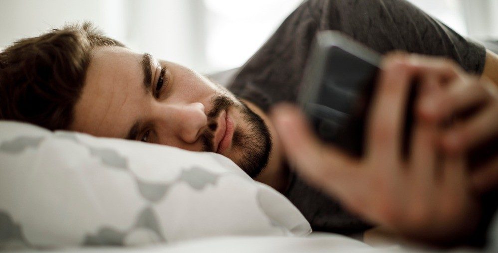 man laying in bed with phone