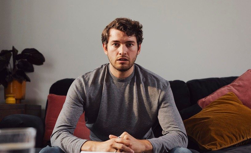 Portrait of young white man with beard, looking towards camera, he looks worried.