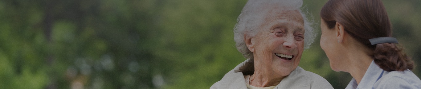 Older woman outside, smiling with her daughter.