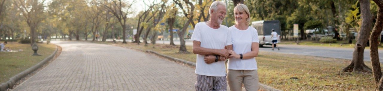 Older couple smiling and going on a walk in the park